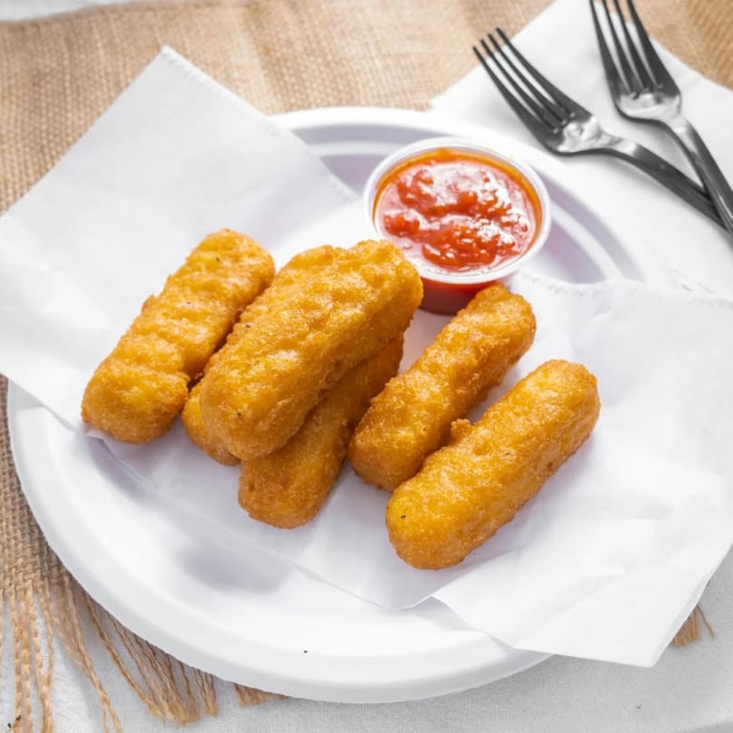 Golden brown mozzarella sticks with a side of red marinara sauce on a white plate.